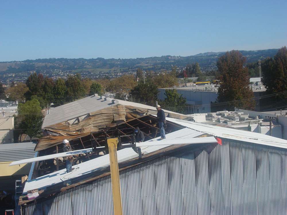 damaged-metal-roof-repair Repairs underway on metal siding, roof, and structure