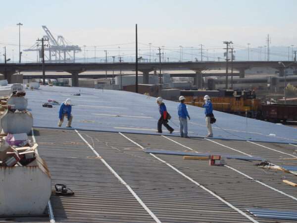 Installers lay metal roofing panels with a corrugated seem